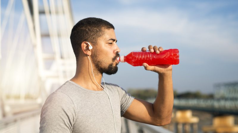 Atleta che beve da una bottiglia rossa