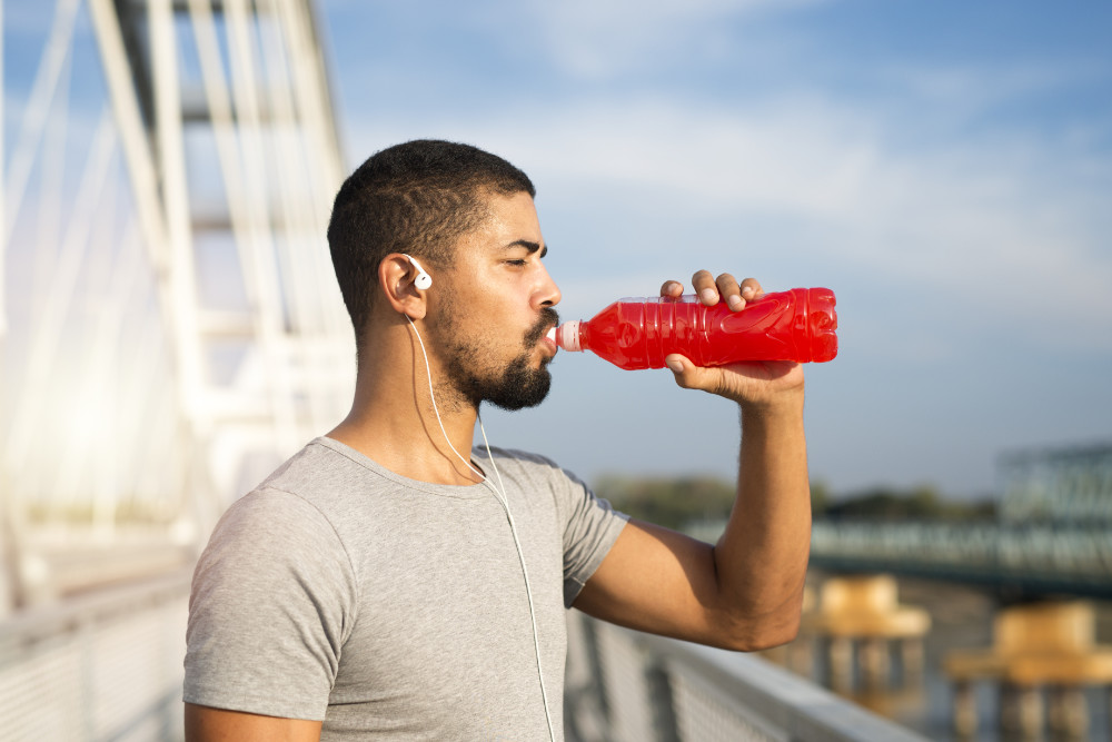 Atleta che beve da una bottiglia rossa